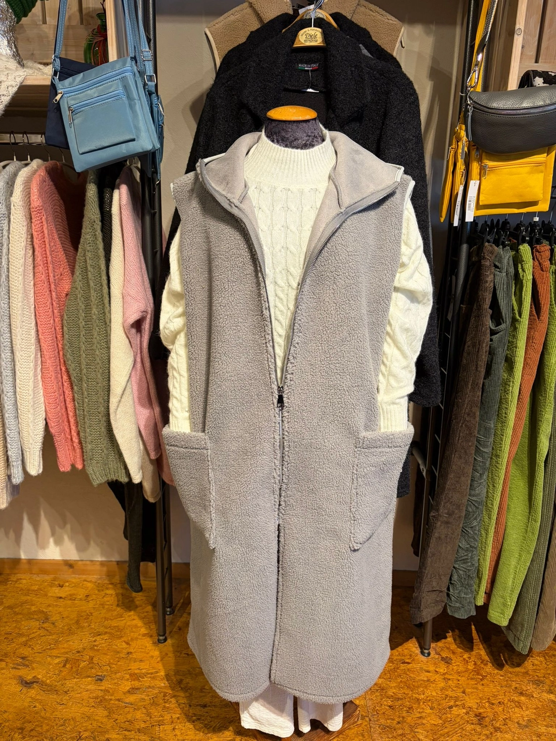 Mode & Handarbeitsdiele - Wolle, Kunsthandwerk, Mode und Accessoires - Ein grauer, ärmelloser Mantel, ausgestellt an einer Schaufensterpuppe.