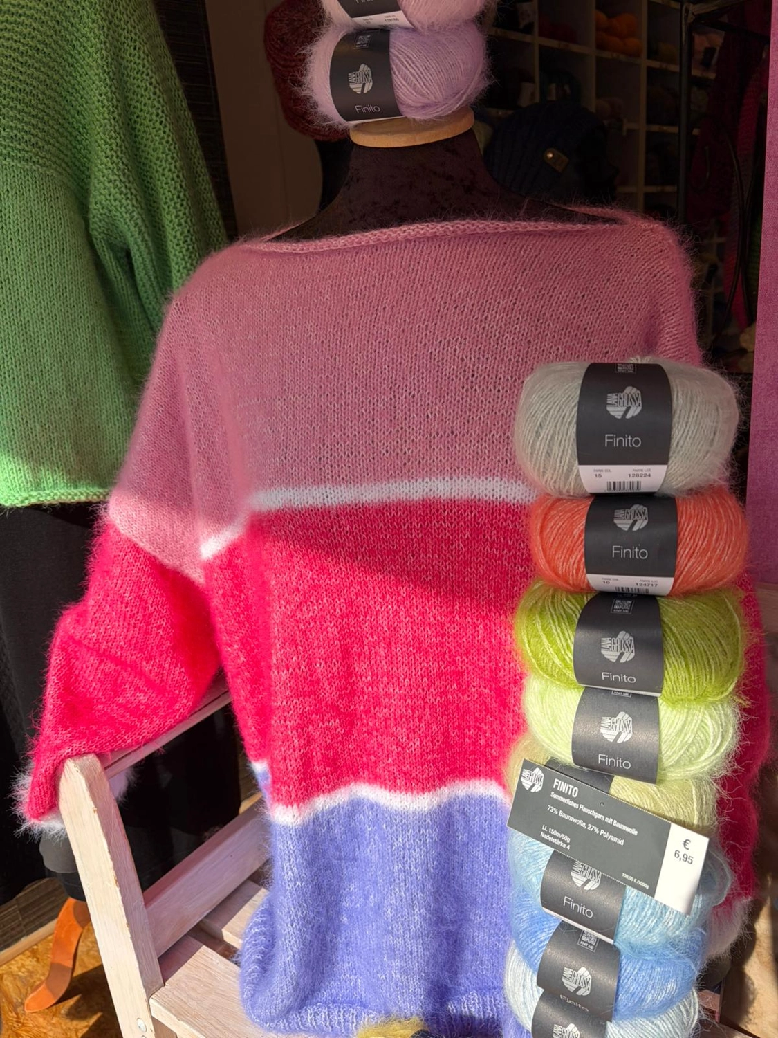 Mode & Handarbeitsdiele - Wolle, Kunsthandwerk, Mode und Accessoires - Rosa Pullover: Ein flauschiger, übergroßer rosa Ombré-Pullover neben mehreren Knäueln passender Wolle.