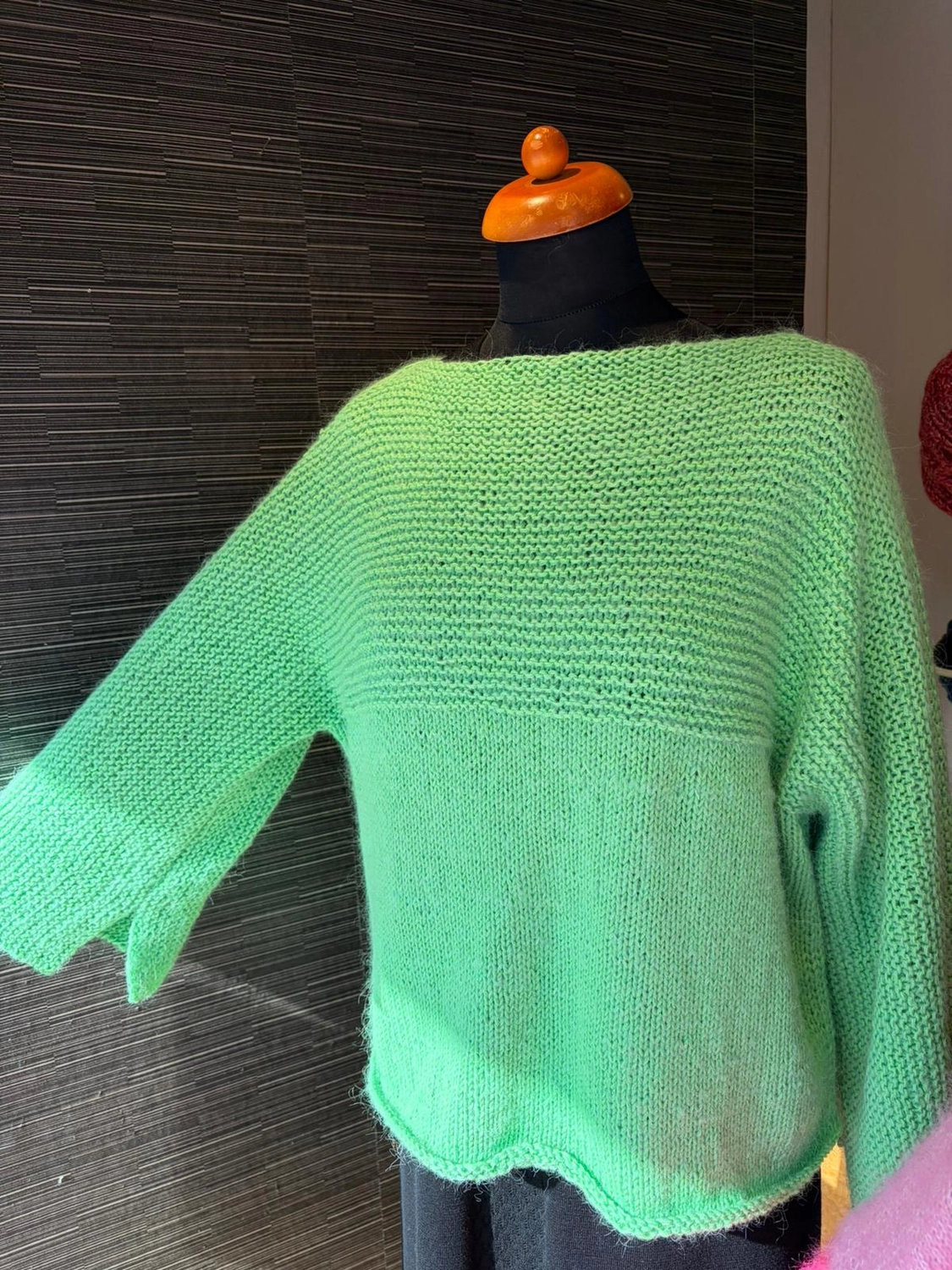 Mode & Handarbeitsdiele - Wolle, Kunsthandwerk, Mode und Accessoires - Grüner Pullover: Ein limettengrüner, grob gestrickter Pullover mit weiten Ärmeln, präsentiert an einer Schaufensterpuppe.