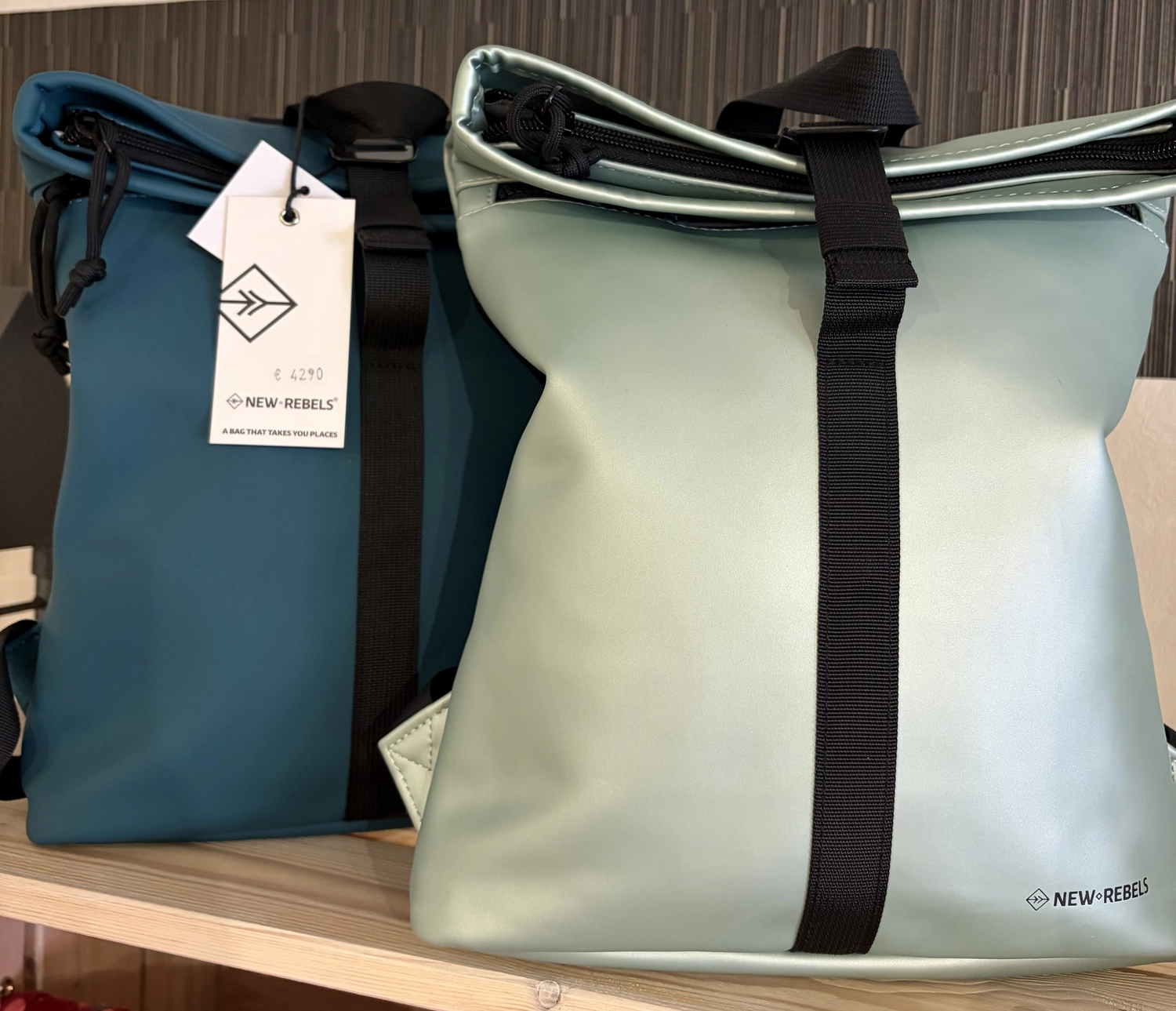 Mode & Handarbeitsdiele - Wolle, Kunsthandwerk, Mode und Accessoires - Zwei Rolltop-Rucksäcke, einer in Türkis und einer in hellem Mintgrün, nebeneinander mit einem Markenetikett.