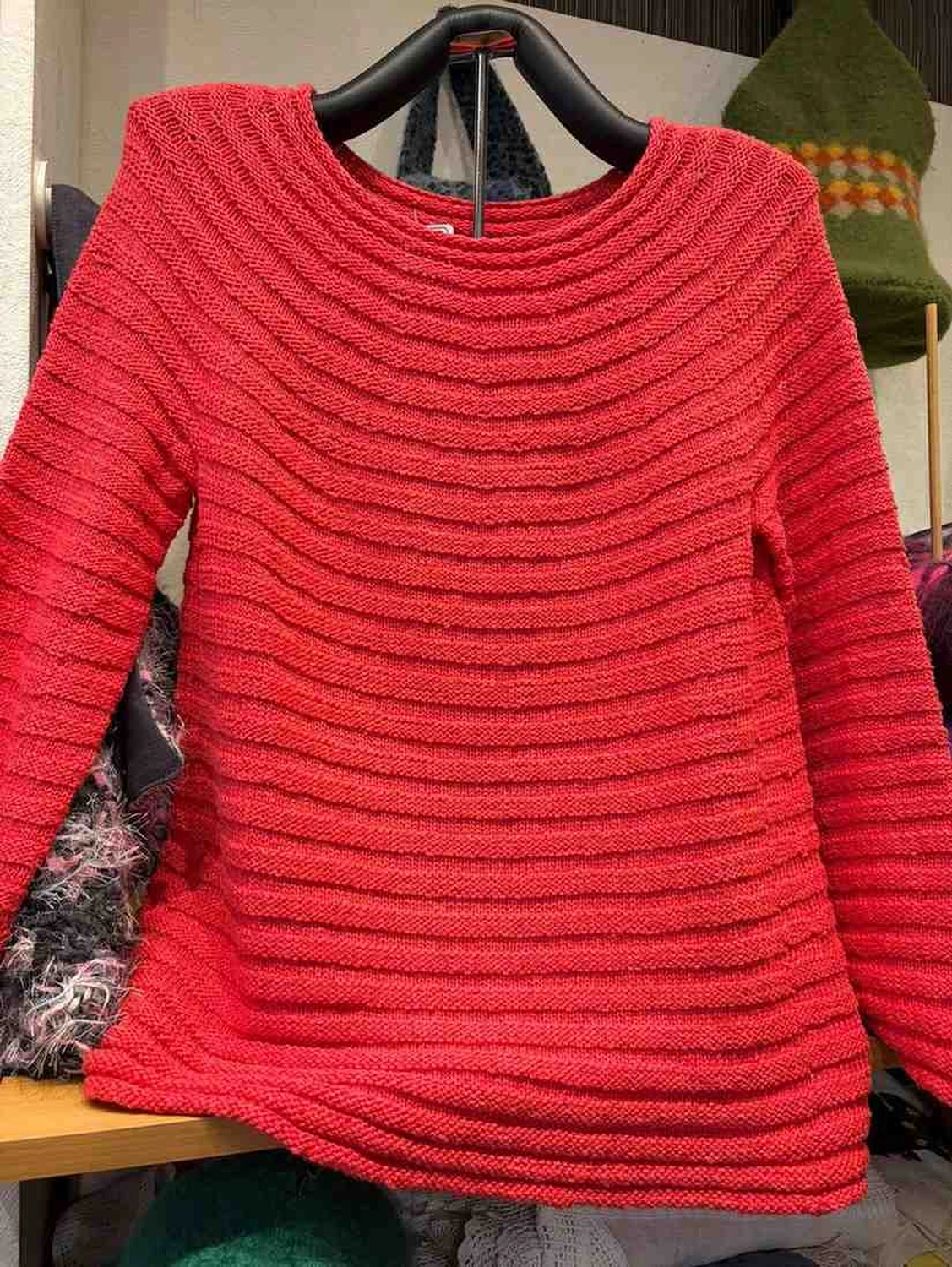 Mode & Handarbeitsdiele - Wolle, Kunsthandwerk, Mode und Accessoires - Roter Pullover: Ein leuchtend roter, langärmeliger Strickpullover mit markanter horizontaler Rippenstruktur.